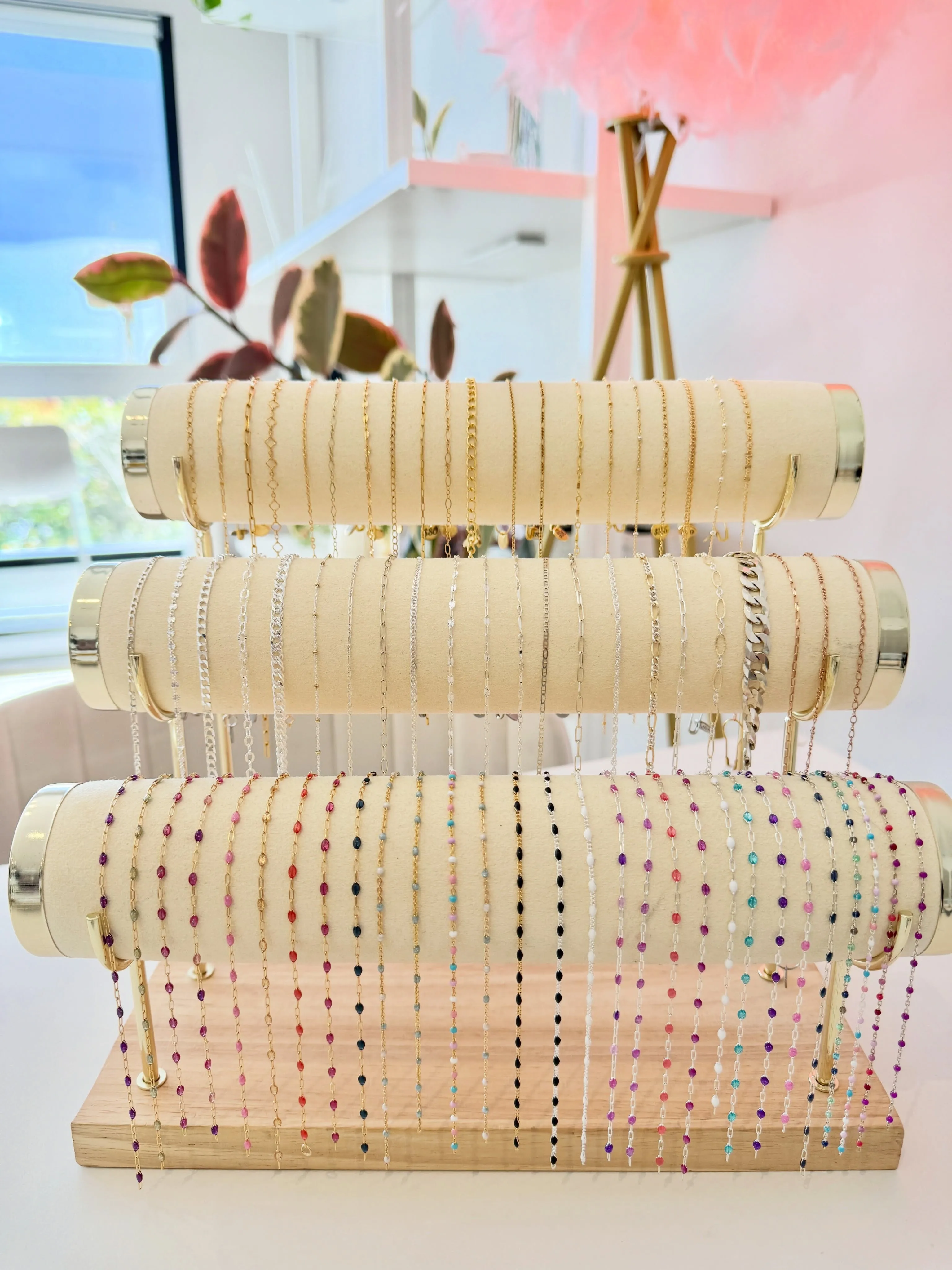 Gold, silver and enamel chains on cream suede rolls in the Dirty Bird studio, pink feather chandelier above