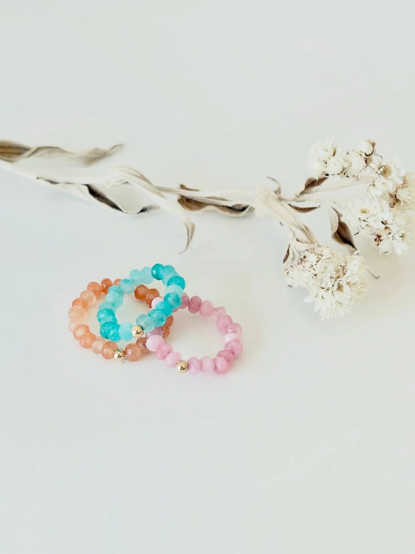 Gemstone stretch rings beside dried flowers