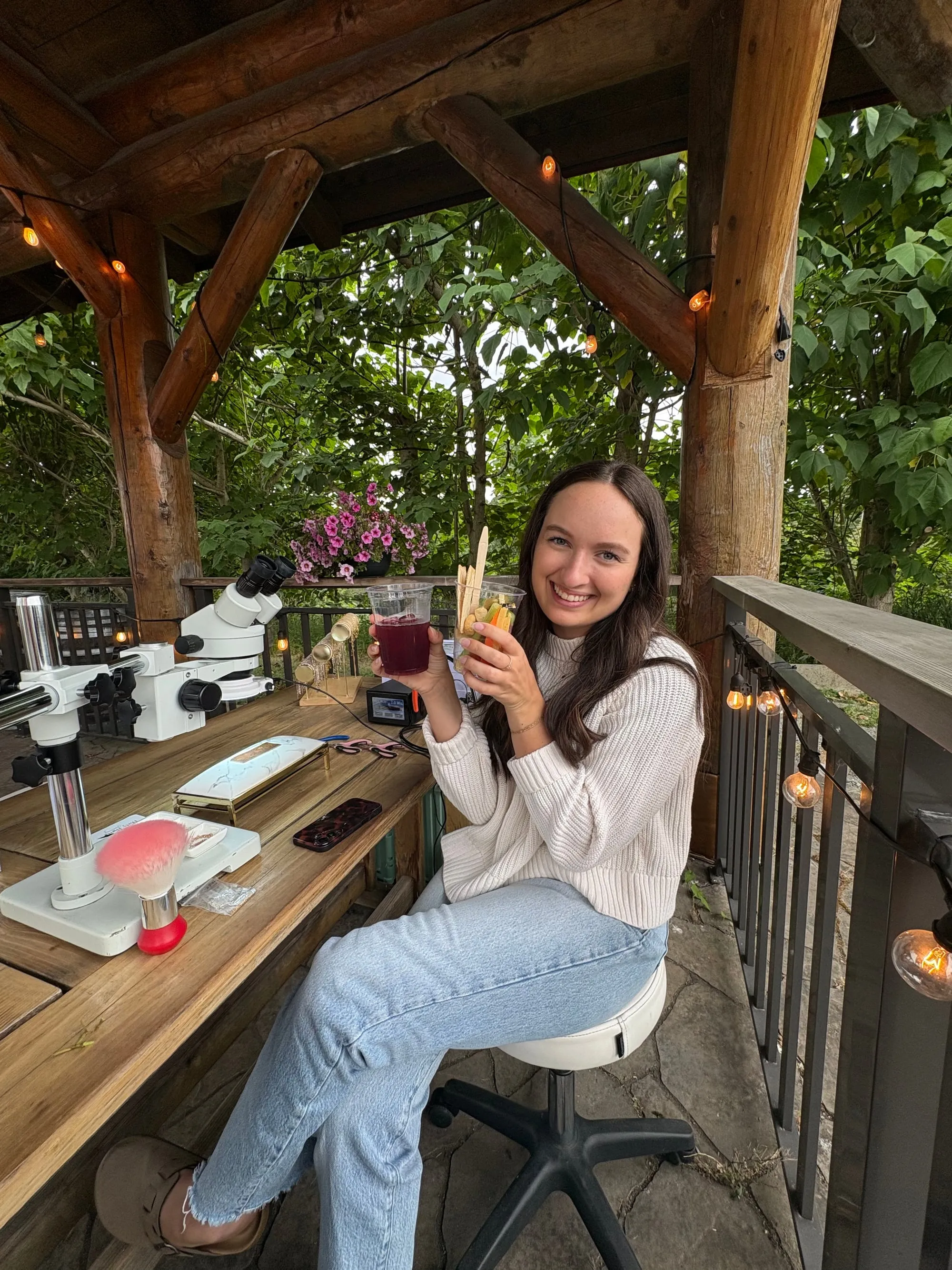 A smiling guest with a drink at the charm bar welding station under the winery pergola